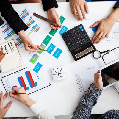 Picture of businessmen's hands on white table with documents, coffee and drafts